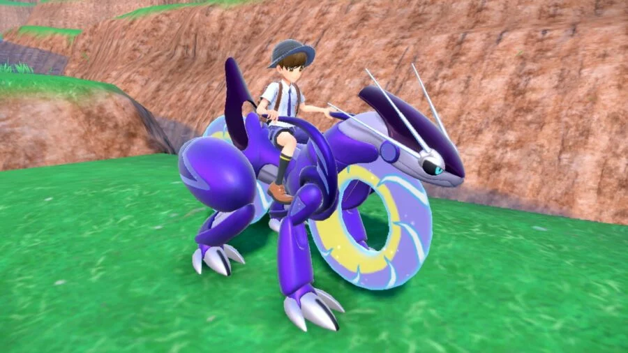 The Pokémon Miraidon. It is a purple Pokémon with four legs and also large wheels, making it act like a motorbike. It is being ridden by a trainer.