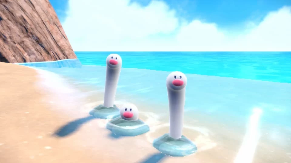 Three of the Pokémon Wiglett. These are stretchy white tubes that come out of the ground with eyes and a round pink nose. They are pictured on the beach near the ocean.