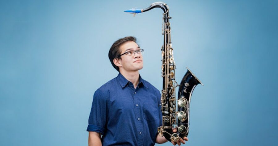Carlos "insaneintherainmusic" Eiene holding a saxophone.