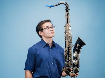 Carlos "insaneintherainmusic" Eiene holding a saxophone.