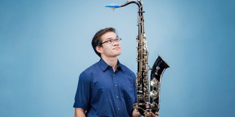 Carlos "insaneintherainmusic" Eiene holding a saxophone.